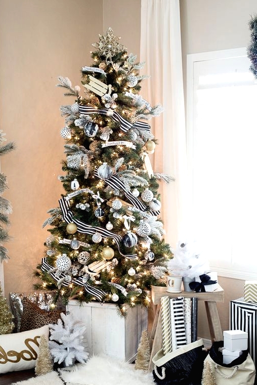 an exquisite Christmas tree with black, white and gold ornaments and cool striped ribbons and lights plus a gold snowflake topper