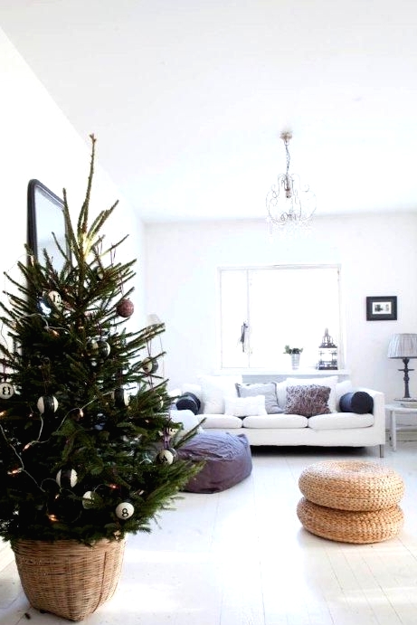 a modern Christmas tree in a basket, with lights, black, white and copper ornaments is a simple and cool idea for a modern space