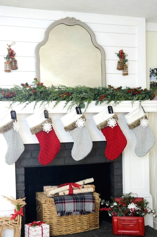 an evergreen garland with berries, red and grey stockings, a basket and firewood, a red chest with evergreens