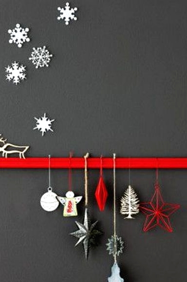 a matte grey wall with a red ribbon and white, red and silver ornaments, white snowflakes on the wall and a white deer on the ribbon are all cool for Christmas