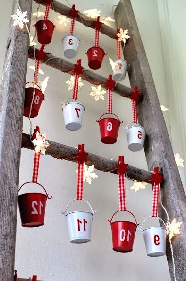 a creative advent calendar with white and red buckets hanging, with star-shaped lights and numbers on the buckets is a very cool solution
