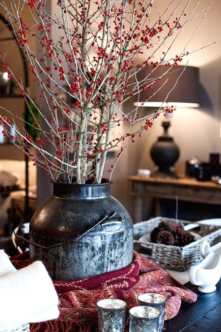 a vintage churn with grey branches and red berries on them is a lovely decor idea for Christmas, it can be your centerpiece