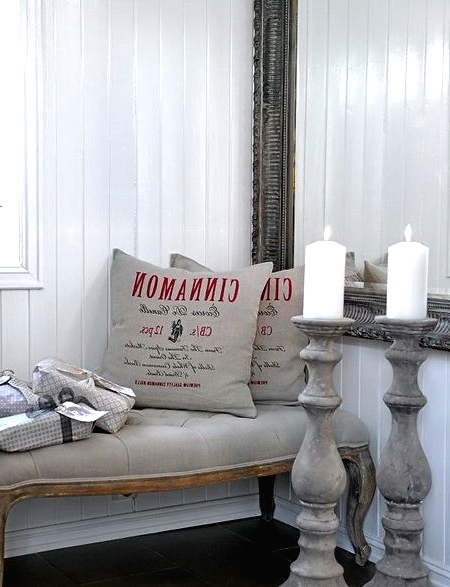 grey pillows with red prints on them, a refined grey bench with gifts and tall wooden candleholders for sophisticated vintage-inspired Christmas decor