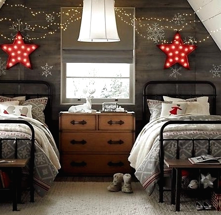 a grey reclaimed wood accent wall with red marquee stars, lights and red and grey Christmas-themed bedding