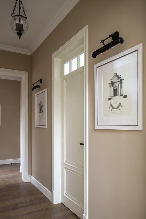 a stylish greige entryway with white touches, artworks and a vintage pendant lamp is a chic space with an elegant color scheme