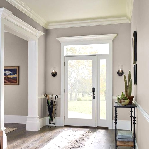 an elegant and lovely greige entryway with white frames and doors in white frames, a black console, artworks and umbrellas