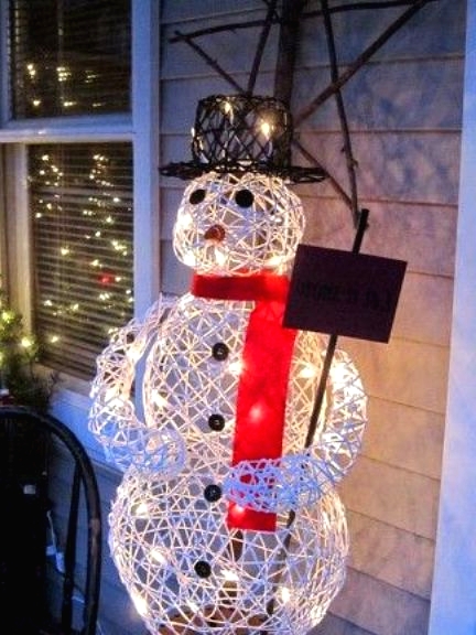 a lit up yarn snowman with a red scarf and a black top hat is a creative outdoor decoration for Christmas