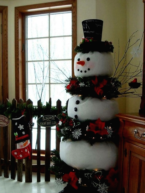 a alrge and bold snowman decoration with evergreens, snowflakes and red blooms, twigs and a tall hat with words is a cool idea for outdoors and indoors