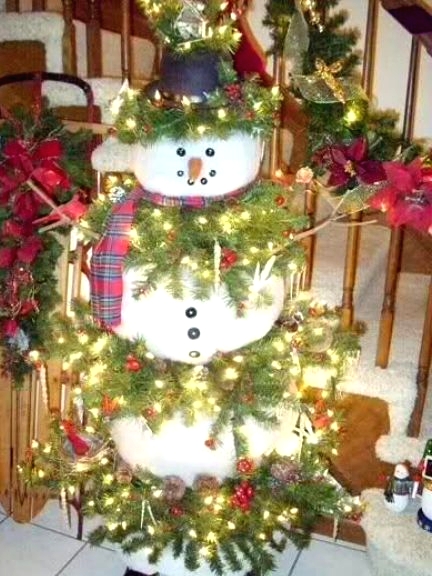 a unique snowman Christmas tree with evergreen branches with lights tucked in between the snowman parts, with pinecones, red bows and hats is a cool solution