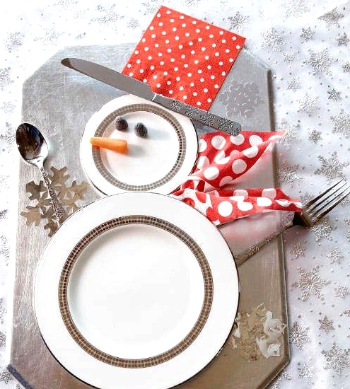 a pretty Christmas place setting with a silver board, a snowman of plates and some bright touches is a cool idea for a modern winter wedding