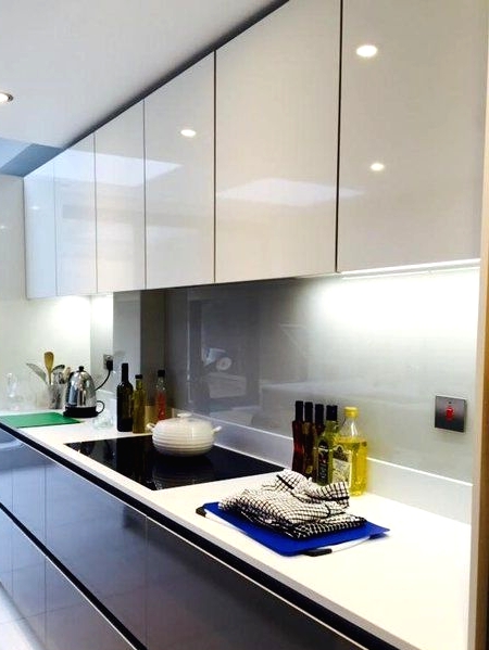 a modern two-tone kitchen with glossy white and matte black cabinets and a grey glass backsplash and white stone countertops