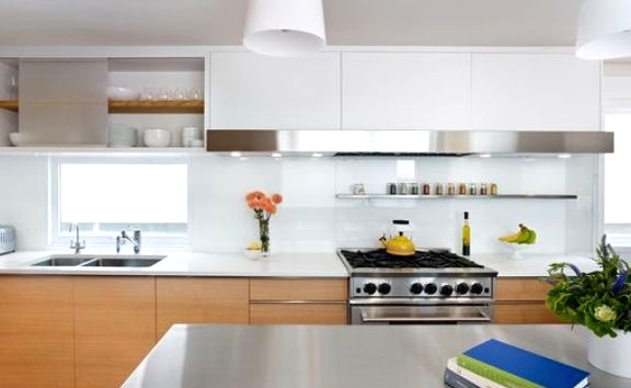 a modern light-stained kitchen with white stone countertops and a glossy white glass backsplash is a chic space with much style