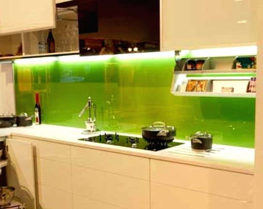 a modern white kitchen with sleek white cabinets, a bold green glass lit up backsplash for a touch of color and a more modern feel