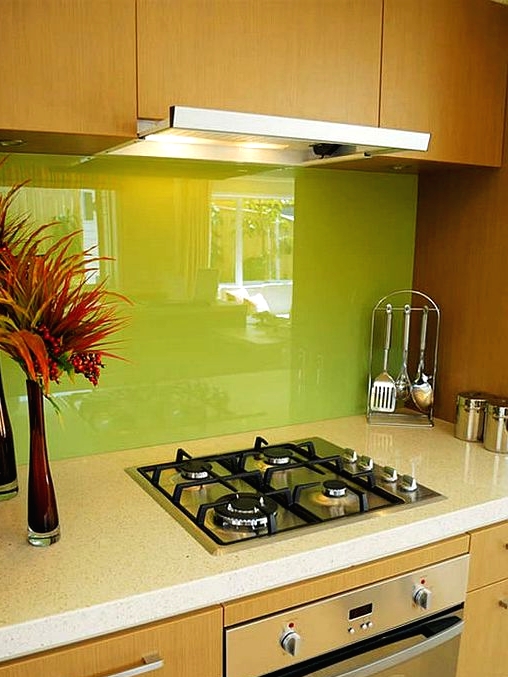 a light-stained kitchen with white stone countertops and a neon green solid glass backsplash for a bold and chic touch of color