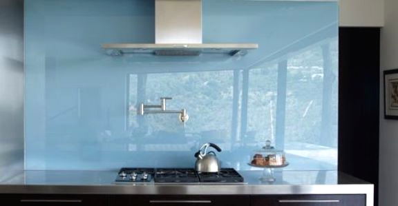 a dark stained kitchen with stainless steel appliances, a glossy blue glass backsplash for a more modern feel