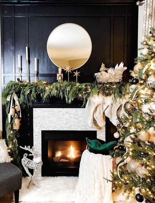 a refined dressed up Christmas mantel with a lush evergreen garland with lights, oversized bells and ribbons and candles in chic candleholders