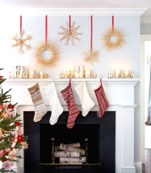 a glam Christmas mantel with mercury glass candleholders, gold wreaths on red ribbons hanging over the mantel and red and gold stockings on the mantel for a timelessly chic look