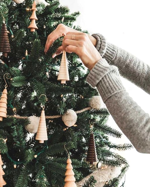 a woodland Christmas tree with pompom garlands, lights, wooden tree-shaped ornaments and burlap ribbons is a creative and cool idea
