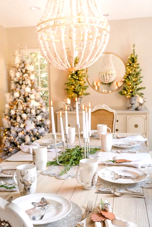 a refined woodland glam Christmas tablescape with silver placemats, printed plates and mugs, wood pinecones and bells plus a modern candelabra is wow