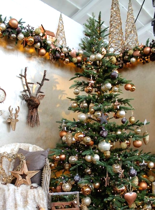 lovely woodland glam Christmas decor with a tree with gold, brown and pearly ornaments, deer heads, ornaent garlands and vine trees