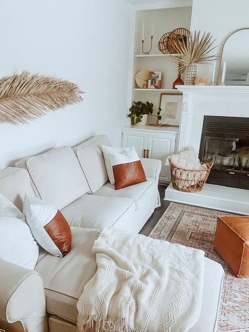 a boho tropical neutral living room with built-in storage units and shelves, a built-in fireplace, a white sectional, brown and amber leather accents