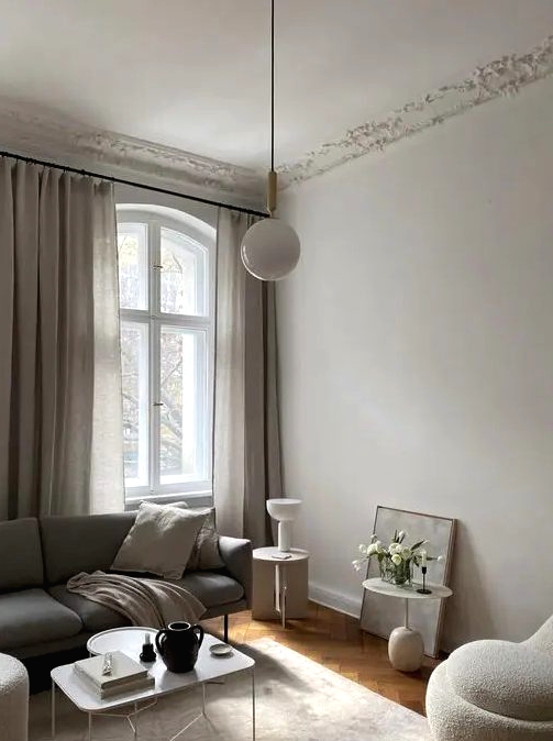 a stylish greige liivng room with a grey sofa, neutral seating furniture, a lightweight coffee table, some pendant and usual lamps