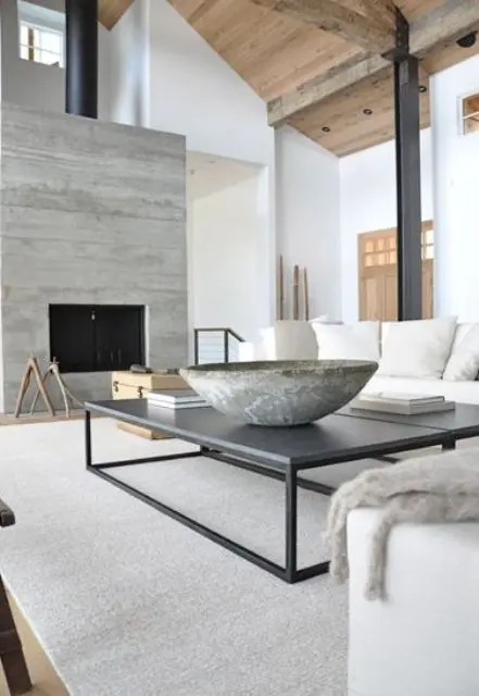 a neutral contemporary living room with a built-in fireplace, neutral seating furniture, a contemporary black coffee table, a stone bowl and a stone accent wall