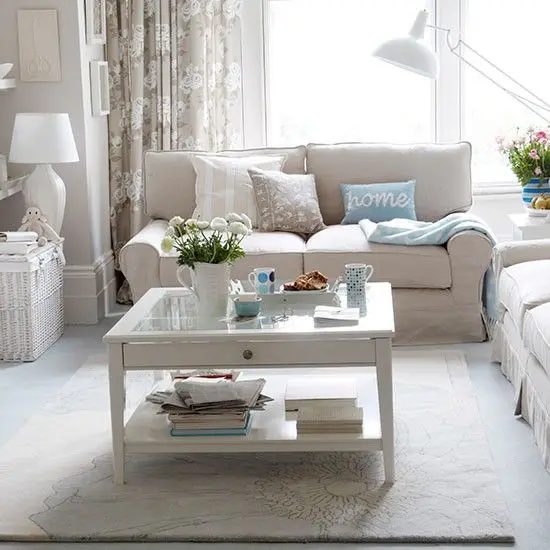 a stylish neutral living room with light grey walls, neutral seating furniture, a tiered coffee table and printed pillows and curtains