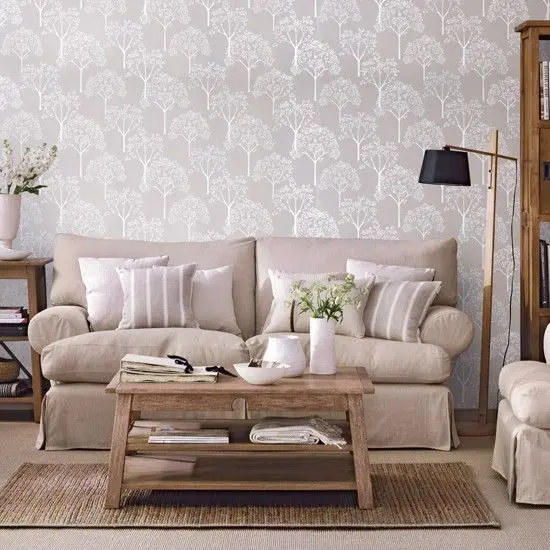 a modern neutral living room with printed wallpaper for an accent, with tan seating furniture, a wooden coffee table and side tables is a welcoming space