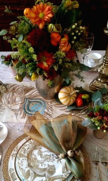 a gold textured charger, gold, blue and white patterned plates and a matching napkin for a super refined and whimsy Thanksgiving table