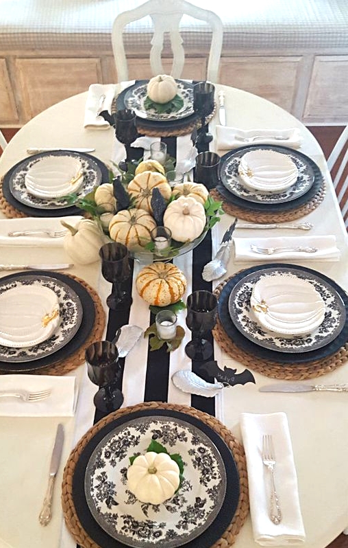 woven placemats, matte black plates and black and white floral ones, a single white pumpkin and small white pumpkin plates on top for a cool fall tablescape