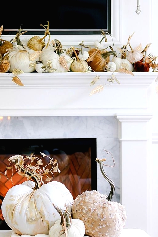 a glam Thanksgiving mantel with white, rust and burgundy velvet pumpkins, gilded leaves and pretty fabric pumpkins in front of it
