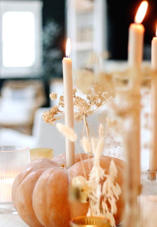 a natural pumpkin with a tall and thin candle and lots of grasses plus candles around is a cool decor idea for Thanksgiving