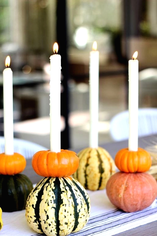 stacked pumpkins with candles integrated are a very natural and very fall-like idea of a Thanksgiving centerpiece that can be DIYed easily