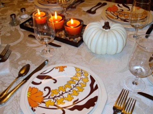 a white faux pumpkin and a tray with pebbles and three colored candles is a delicate and fast Thanksgiving centerpiece