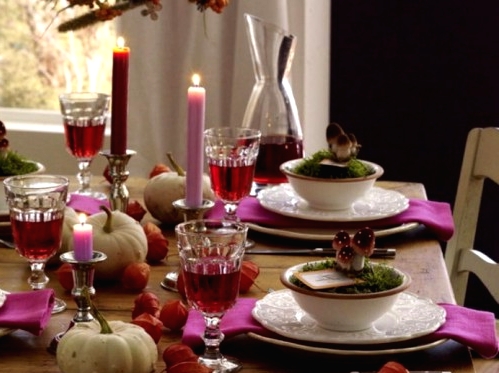 a bright woodland Thanksgiving tablescape with hot pink napkins and hot pink and burgundy candles, mushrooms, seed pods, moss is pretty and bold