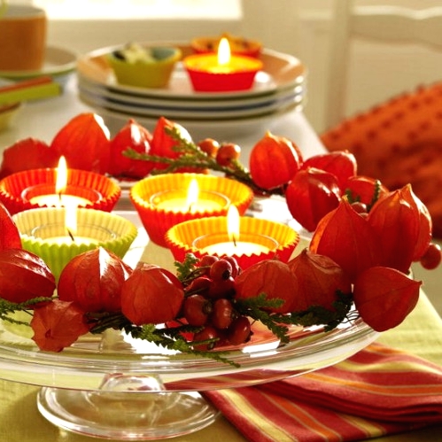 a beautiful Thanksgiving centerpiece of seed pods, greenery, berries and candles in colorful cupcake liners