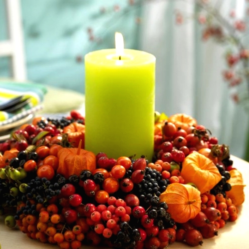a Thanksgiving centerpiece of berries, seed pods and a neon green pillar candle in the center is a bright and cool solution