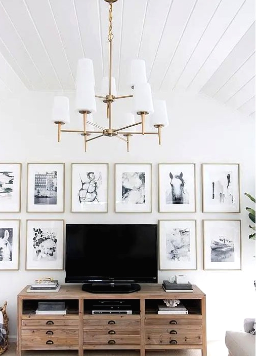 a chic gallery wall with thin gold frames, white matting and black and white photos framing the TV is cool