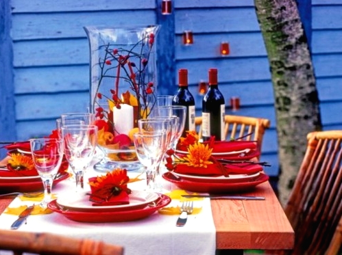 a colorful Thanksgiving tablescape with red porcelain, napkins, blooms, fall leaves and berries is a bright solution