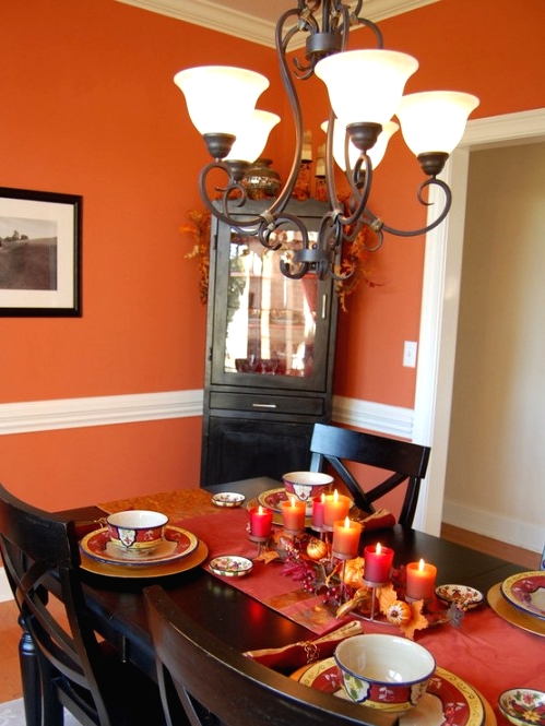 a bold Thanksgiving tablescape with bright linens, printed porcelain, faux pumpkins, leaves and bold pillar candles is a chic and stylish idea