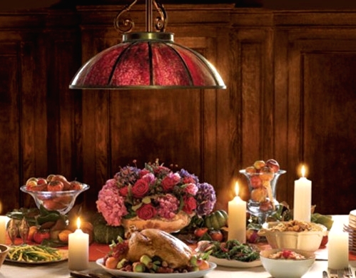 a sophisticated traditional Thanksgiving tablescape with a bold floral centerpiece, candles, pillar candles and a beautiful metal pendant lamp over it