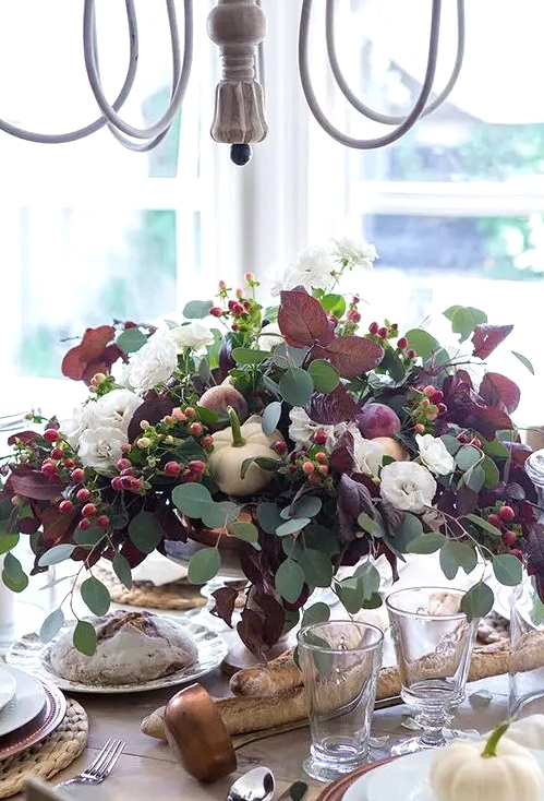 a beautiful and natural Thanksgiving centerpiece of usual and dark foliage, white pumpkins, berries and white blooms