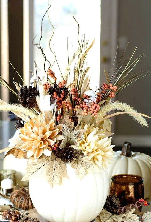 a bold dimensional Thanksgiving centerpiece of a white pumpkin, faux blooms, leaves, berries, real pinecones, twigs and branches