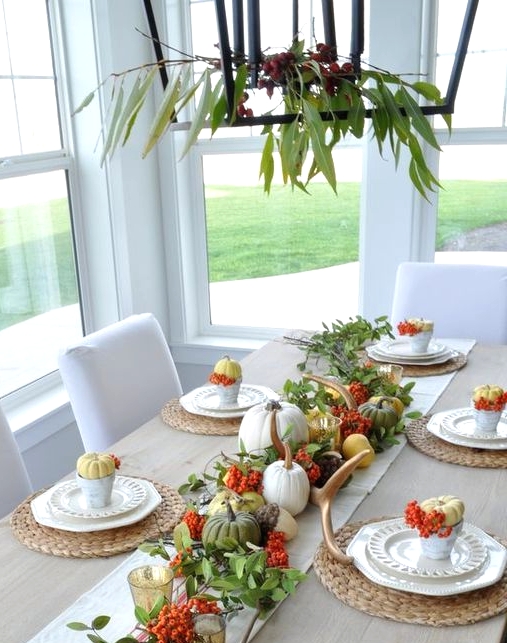 a bold natural Thanksgiving centerpiece and table runner of green, yellow and white pumpkins, berries and greenery plus candles