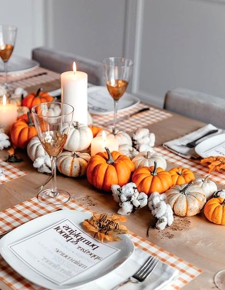 a bold Thanksgiving centerpiece of white and orange mini pumpkins, cotton and pillar candles is a pretty solution for a rustic Thanksgiving tablescape