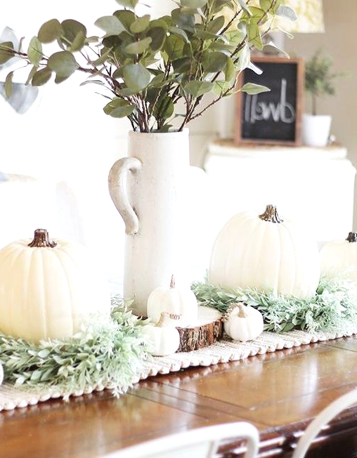 a farmhouse Thanksgiving centerpiece of greenery, white pumpkins and gourds and greenery in a tall jug is awesome