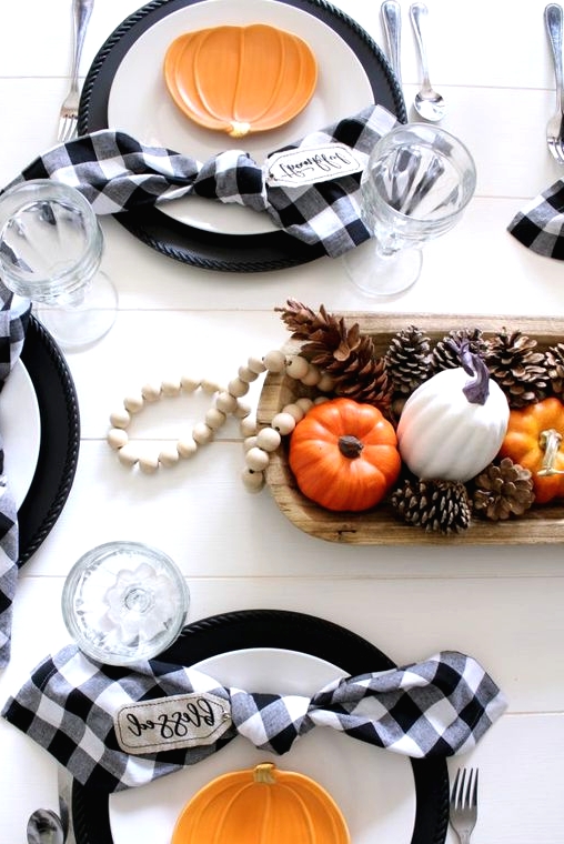 a pretty and cool Thanksgiving centerpiece of a dough bowl with pinecones and faux pumpkins plus some wooden beads is easy to recreate