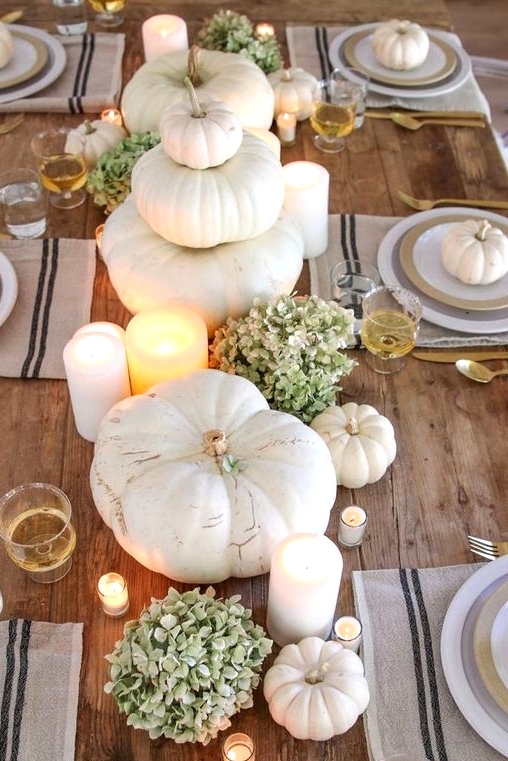 a super easy and fab Thanksgiving centerpiece of white pumpkins, green hydrangeas and various candles is amazing