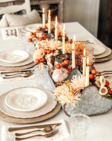 an eye-catchy Thanksgiving centerpiece of a metal tool box with blush and white blooms, berries and tall and thin candles